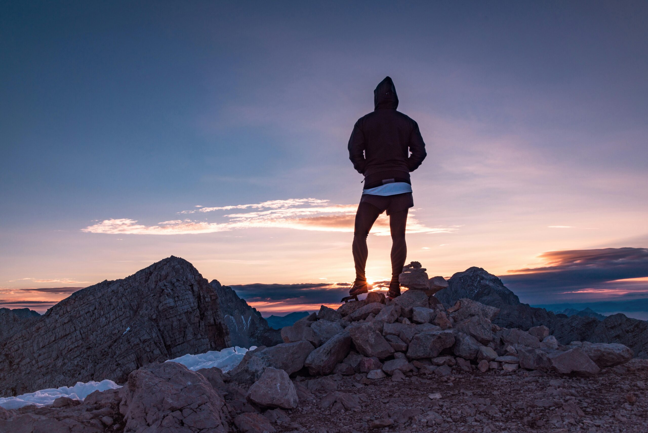 A person standing on top of rocks at sunset.