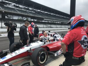 A group of people standing around an indy car.