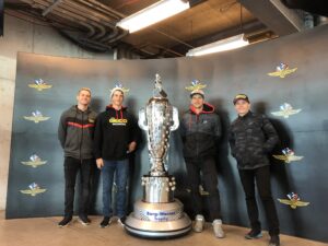 Four men standing next to a large trophy.