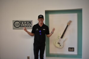 A man standing in front of an electric guitar.