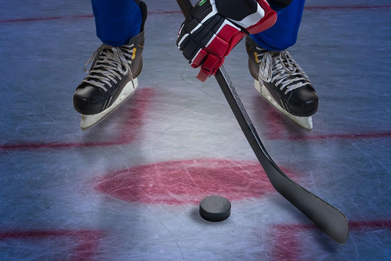 A hockey player is holding his stick and ready to hit the puck.