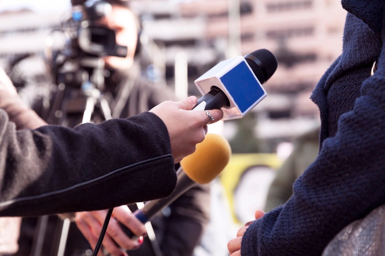 A person holding a microphone and talking to someone.